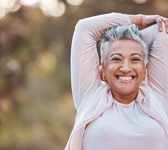  Senior woman standing outside smiling and stretching