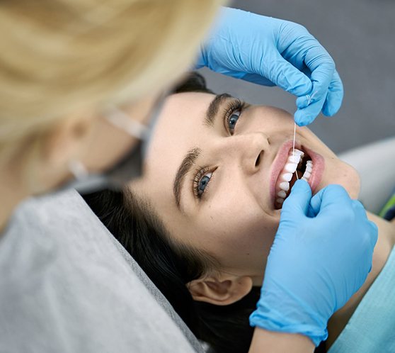 flossing patient’s teeth during dental exam in Austin  