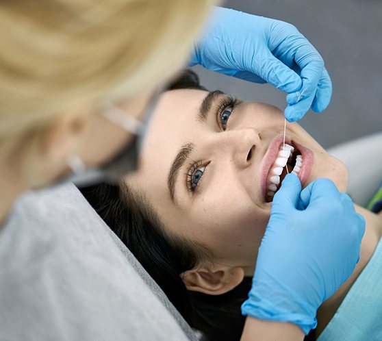 flossing patient’s teeth during dental exam in Austin