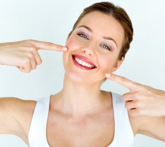 Woman pointing to smile after cosmetic dental bonding