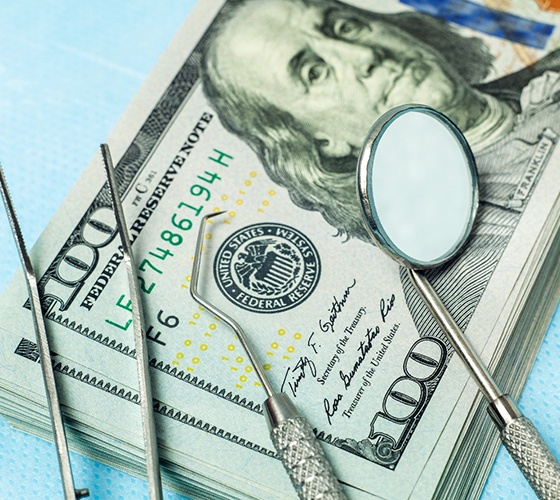 Dental tools sitting on a stack of dollar bills