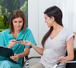 A woman paying the cost of dental crowns