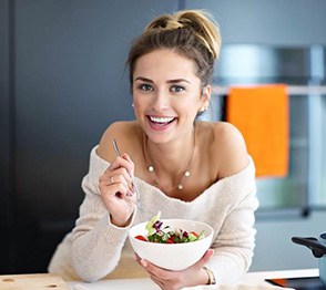 Woman smiling while eating bowl of fruit