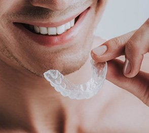 Man holding custom mouthguard from an Austin emergency dentist