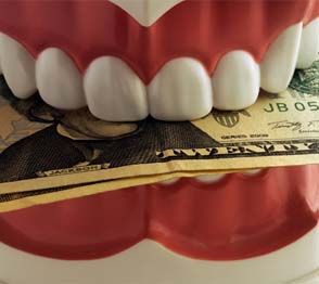 False teeth biting down on dollar bills