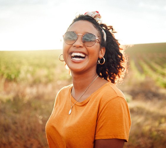 Woman in orange shirt smiling in a field