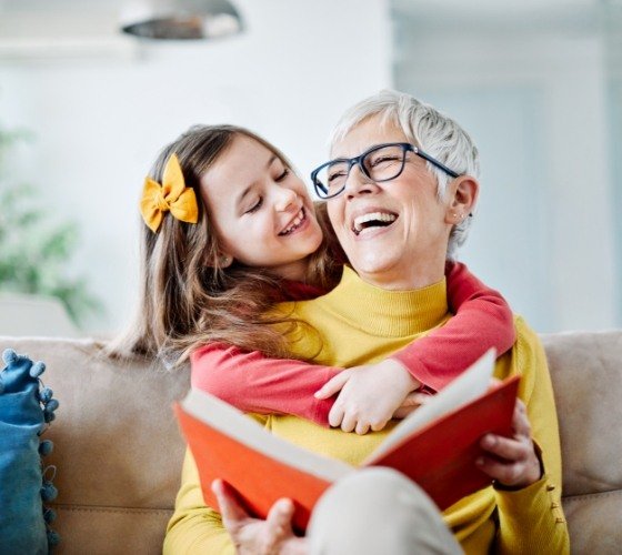 Woman with tooth replacement using dental implants laughing with granddaughter