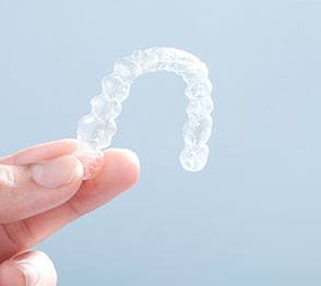 Closeup of patient holding up Invisalign in Austin