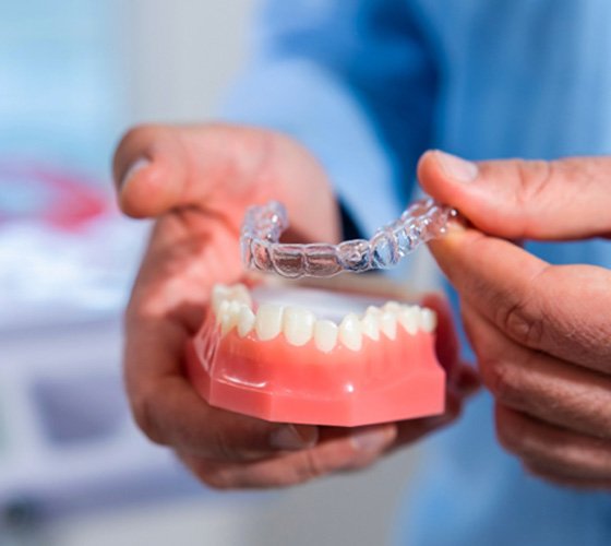 Austin cosmetic dentist placing Invisalign aligner on model of teeth