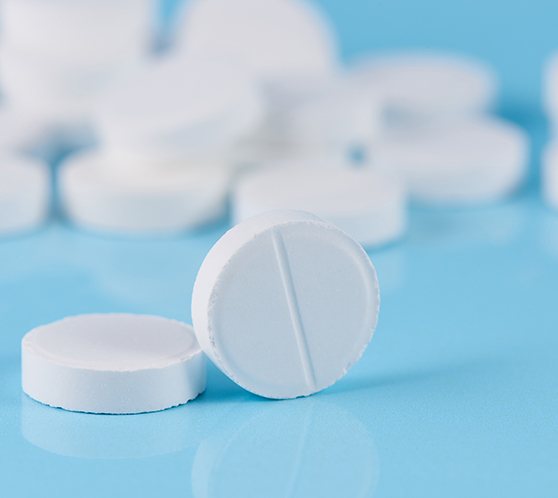 Generic round white pills on a light blue surface