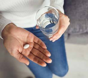 Woman holding a painkiller and glass of water