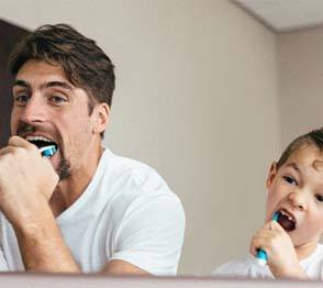 Father and son brushing their teeth together