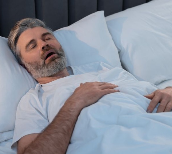 Older man snoring in bed