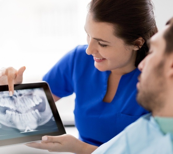 Dentist and patient looking at digital x-rays on tablet computer