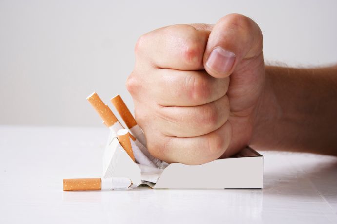 A hand crushing a pack of cigarettes