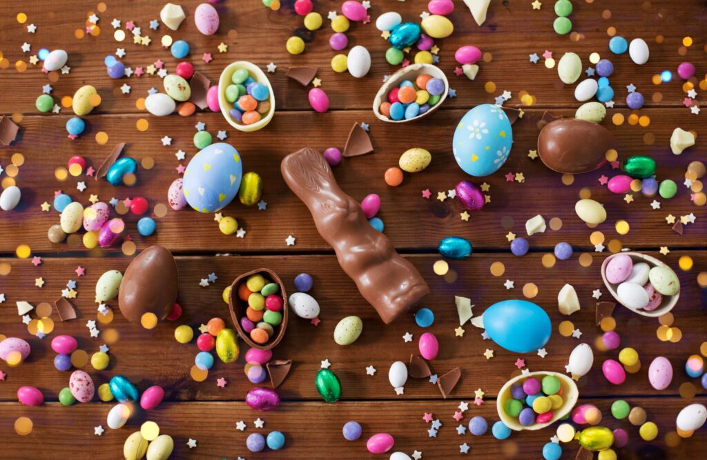 Bird's eye view of a lot of easter chocolate bunnies and eggs on a wooden surface
