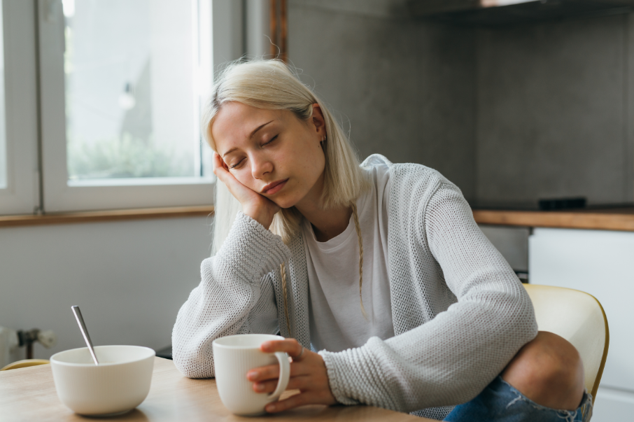 Woman falling asleep at table with coffee